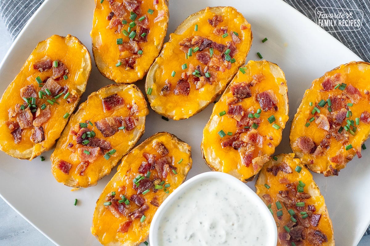 Loaded potato skins on a plate with a side of ranch dressing.