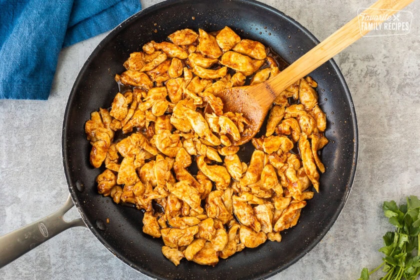 Skillet with cooked chicken with seasoning.