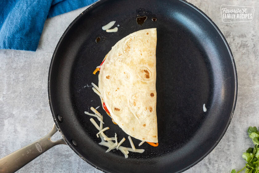 Folded over chicken quesadilla in a skillet.