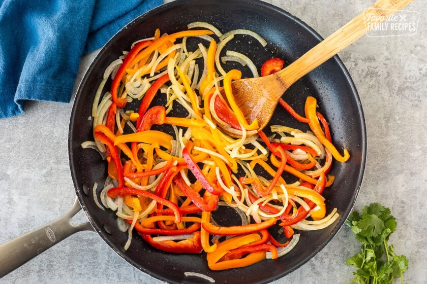 Skillet with sliced bell peppers and onion.