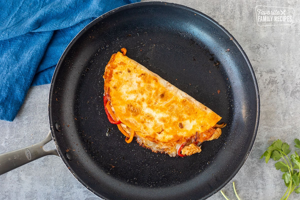 Golden brown chicken quesadilla in a skillet.