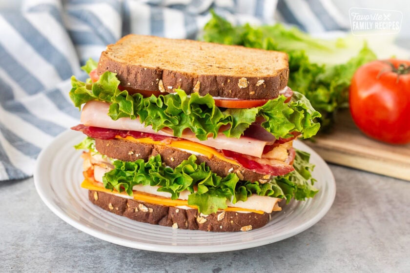 Triple decker club sandwich with wheat bread lightly toasted on a plate.