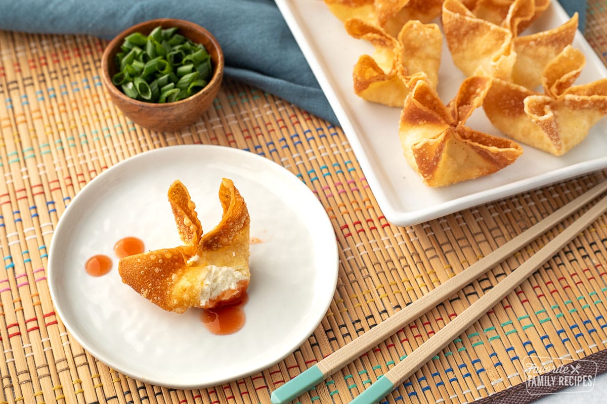 Close up of a cream cheese wonton with a bite taken out of it to show the creamy, cheesy center