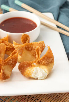 Close up of golden fried cream cheese wontons with one showing the creamy center