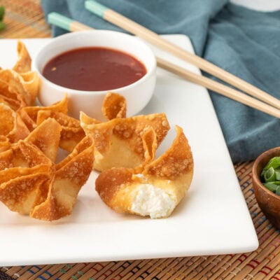 Close up of golden fried cream cheese wontons with one showing the creamy center