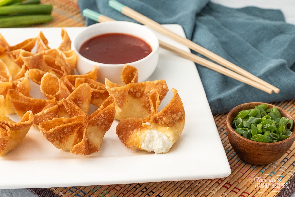 Close up of golden fried cream cheese wontons with one showing the creamy center