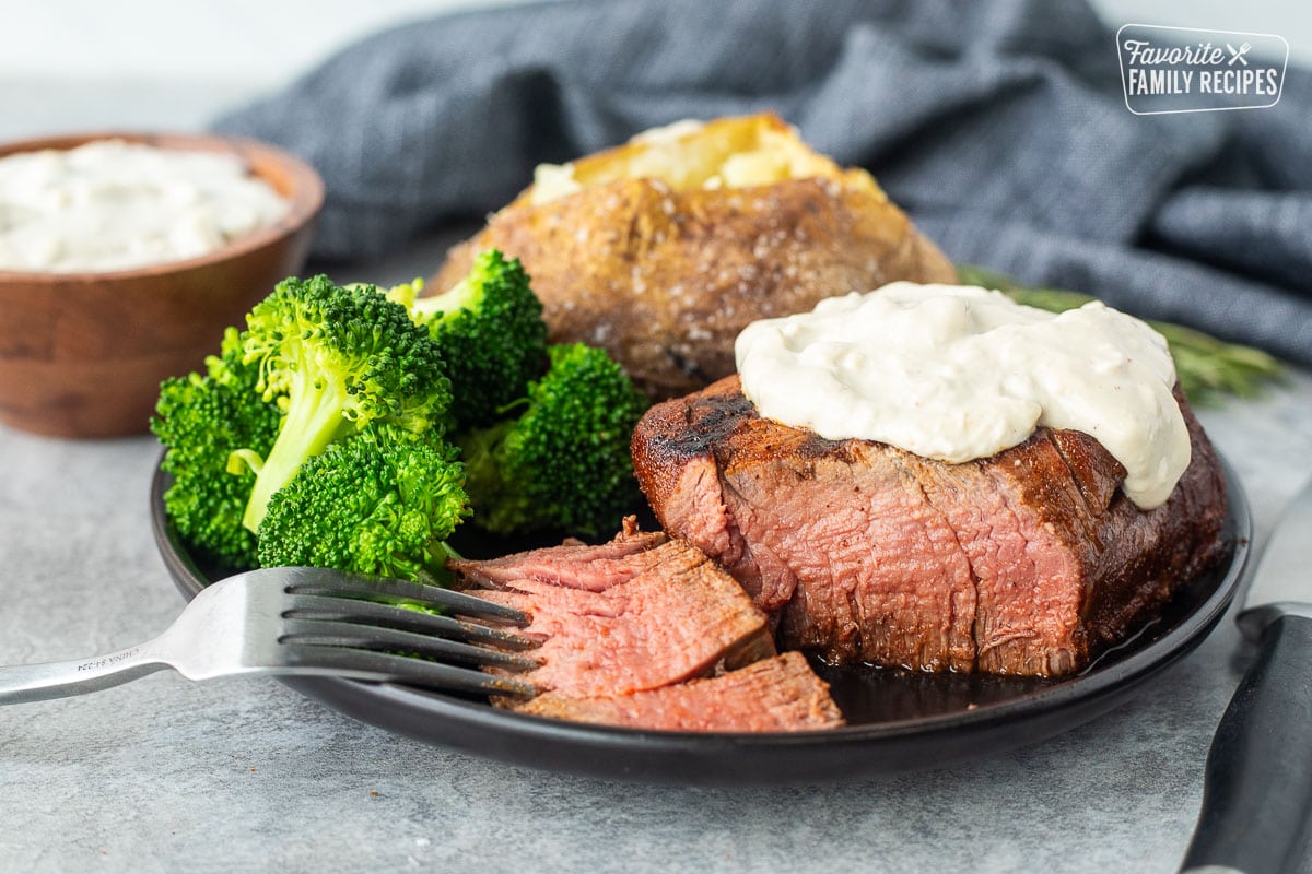 Grilled Filet Mignon with Blue Cheese sauce on a plate with a baked potato and broccoli.