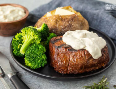 Grilled Filet Mignon with Blue Cheese sauce on a plate with a baked potato and broccoli.