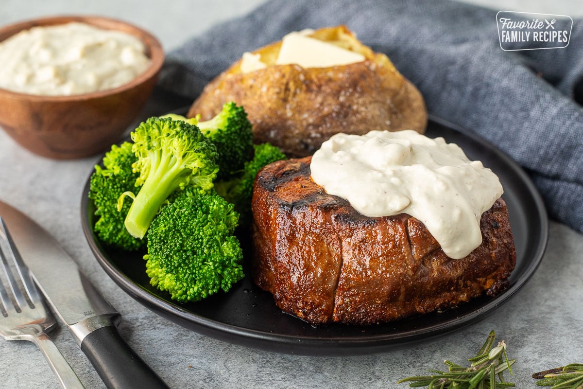 Grilled Filet Mignon with Blue Cheese sauce on a plate with a baked potato and broccoli.