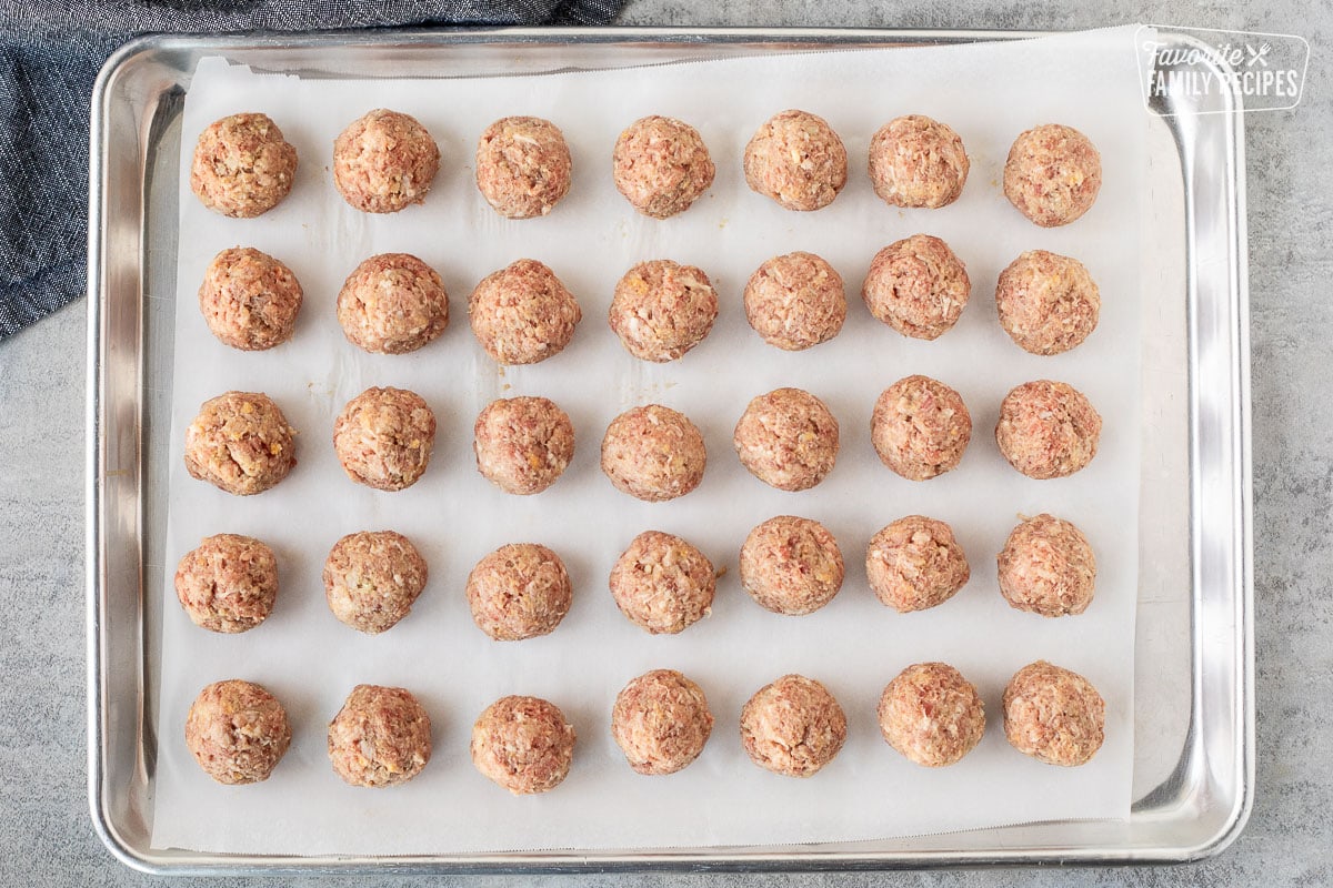 Rows of uncooked meatballs on a lined baking sheet