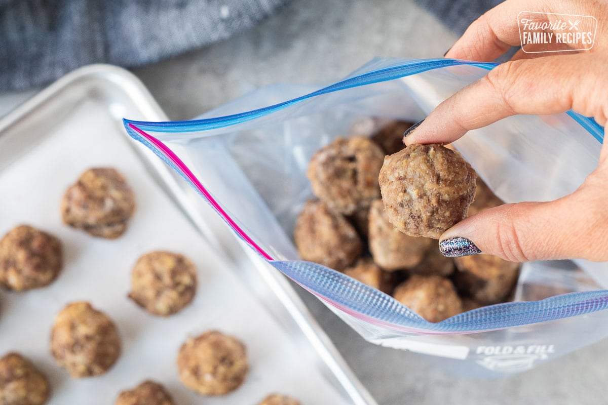 Frozen meatballs being pulled from a freezer bag, ready to be reheated and eaten