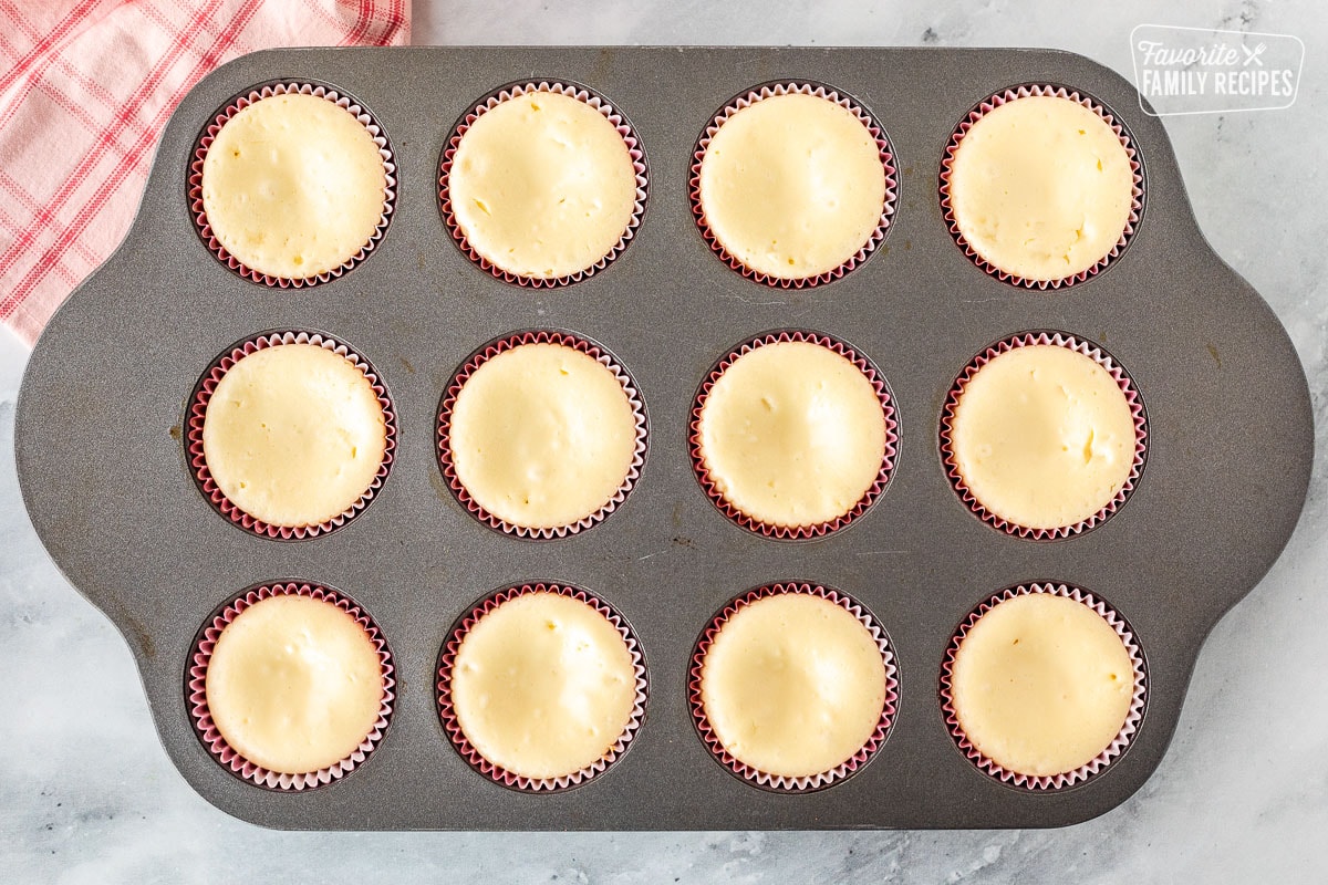 A baking pan of baked mini cheesecakes.