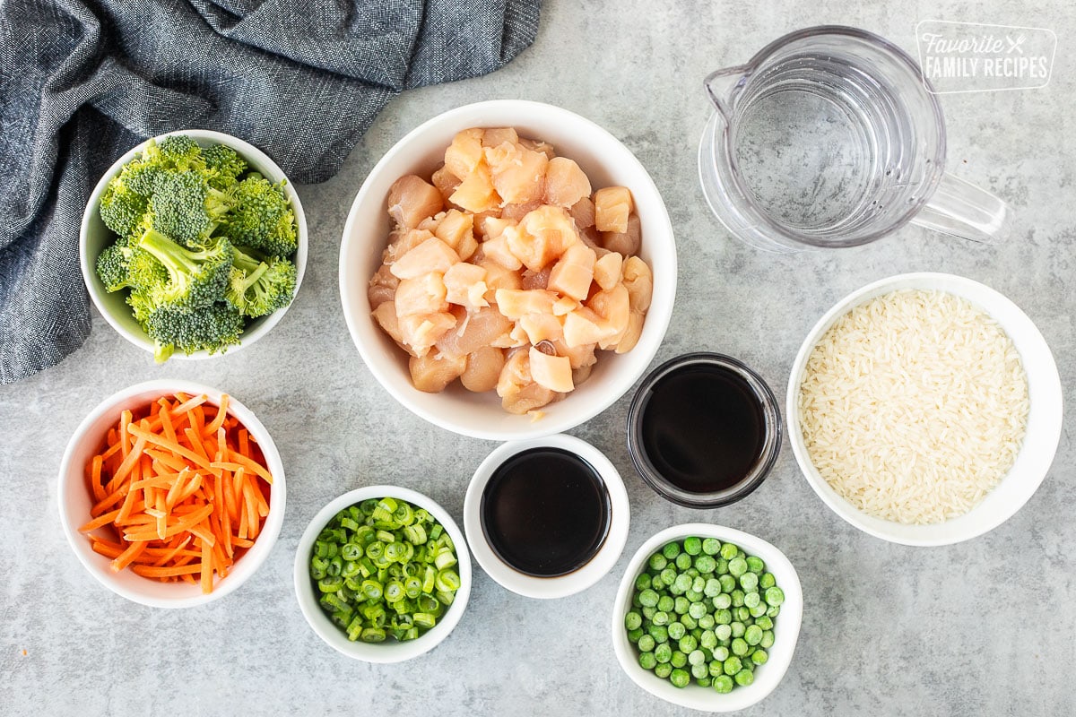 Ingredients to make One Pot Teriyaki Chicken Bowls including chicken breast, broccoli, carrots, green onions, peas, rice, teriyaki sauce, soy sauce and water.