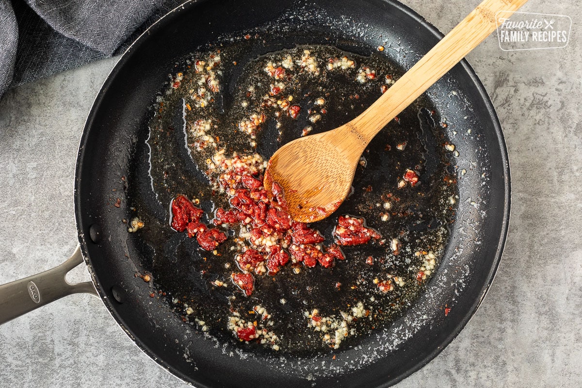 Skillet with butter melted, garlic and tomato paste.