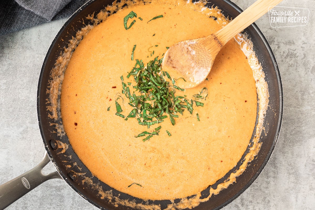 Skillet with ravioli sauce and fresh sliced basil.