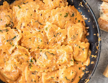 Skillet of fresh ravioli tossed in a ravioli sauce with fresh basil pepper and cheese.