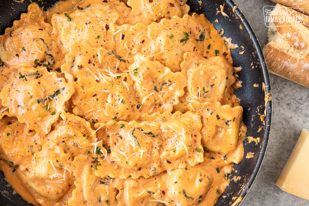 Skillet of fresh ravioli tossed in a ravioli sauce with fresh basil pepper and cheese.