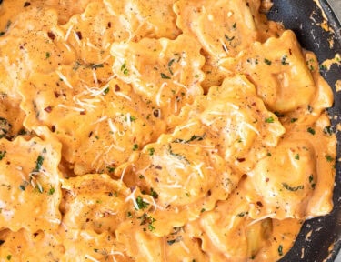 Skillet of Ravioli tossed in a tomato cream sauce with fresh basil and cheese.