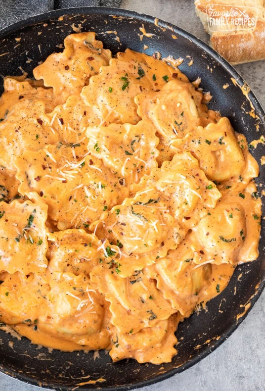 Skillet of Ravioli tossed in a tomato cream sauce with fresh basil and cheese.