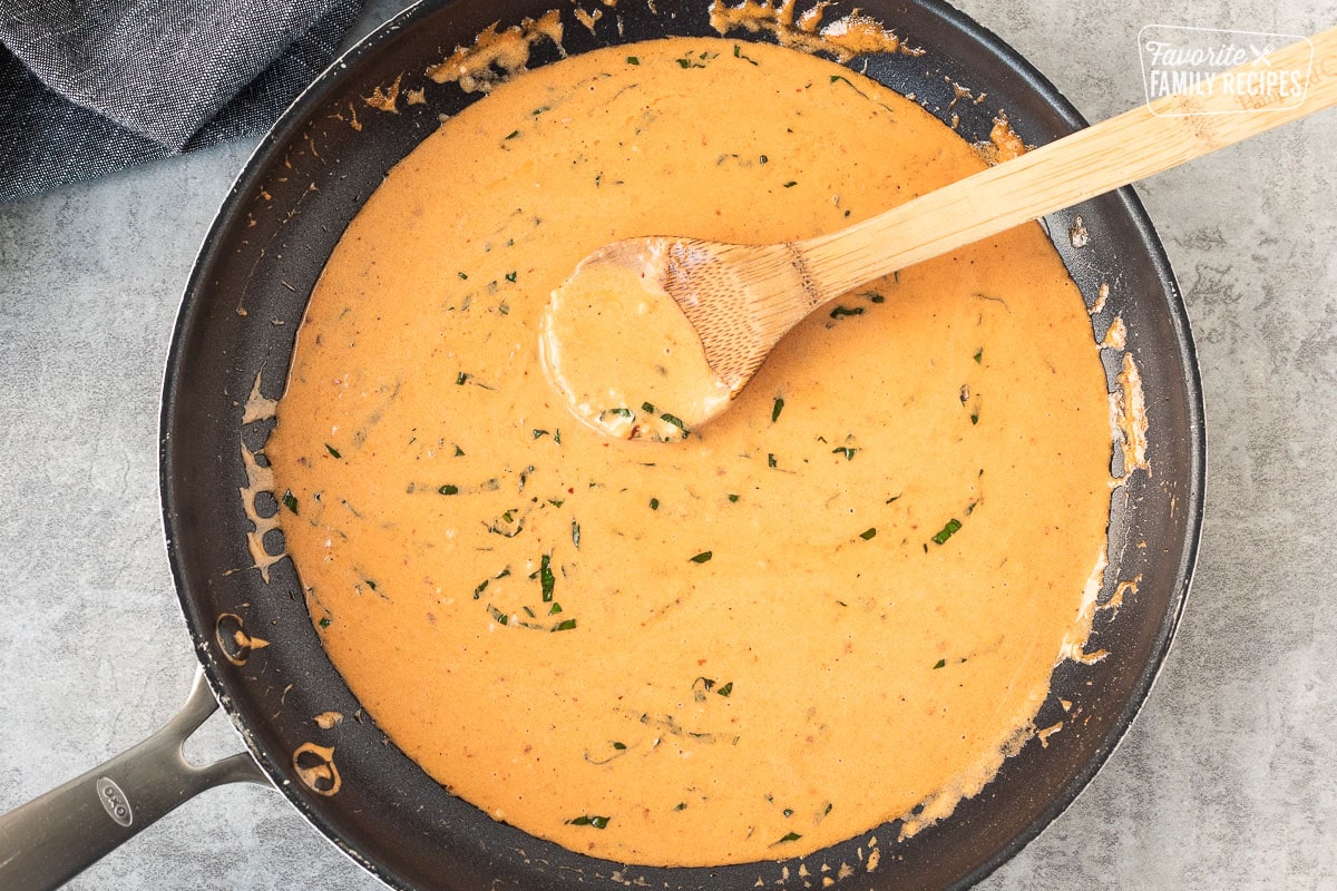 Ravioli sauce and skillet with a wooden spoon.