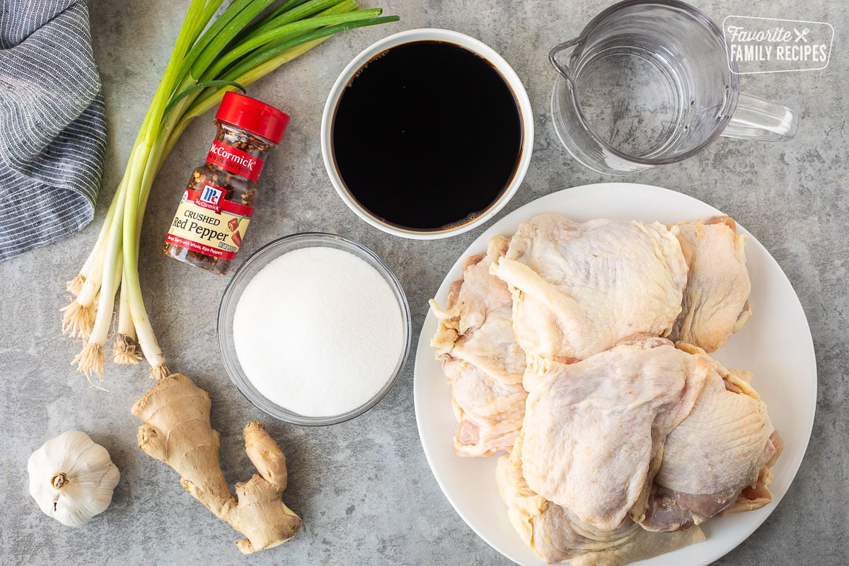 Ingredients to make Shoyu chicken including chicken thighs with skin, soy sauce, water, sugar, ginger, garlic, green onion and crushed red pepper.