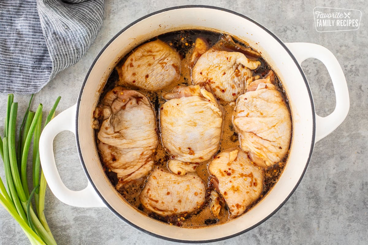 Dutch oven with Shoyu chicken base and seven chicken thighs with skin.