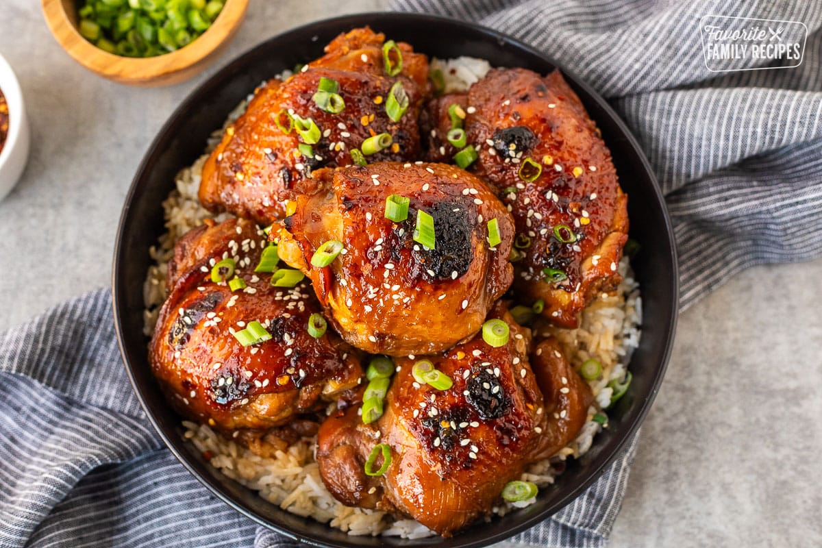 Plate with white rice and five pieces of Shoyu chicken topped with fresh slices of green onion and sesame seeds.