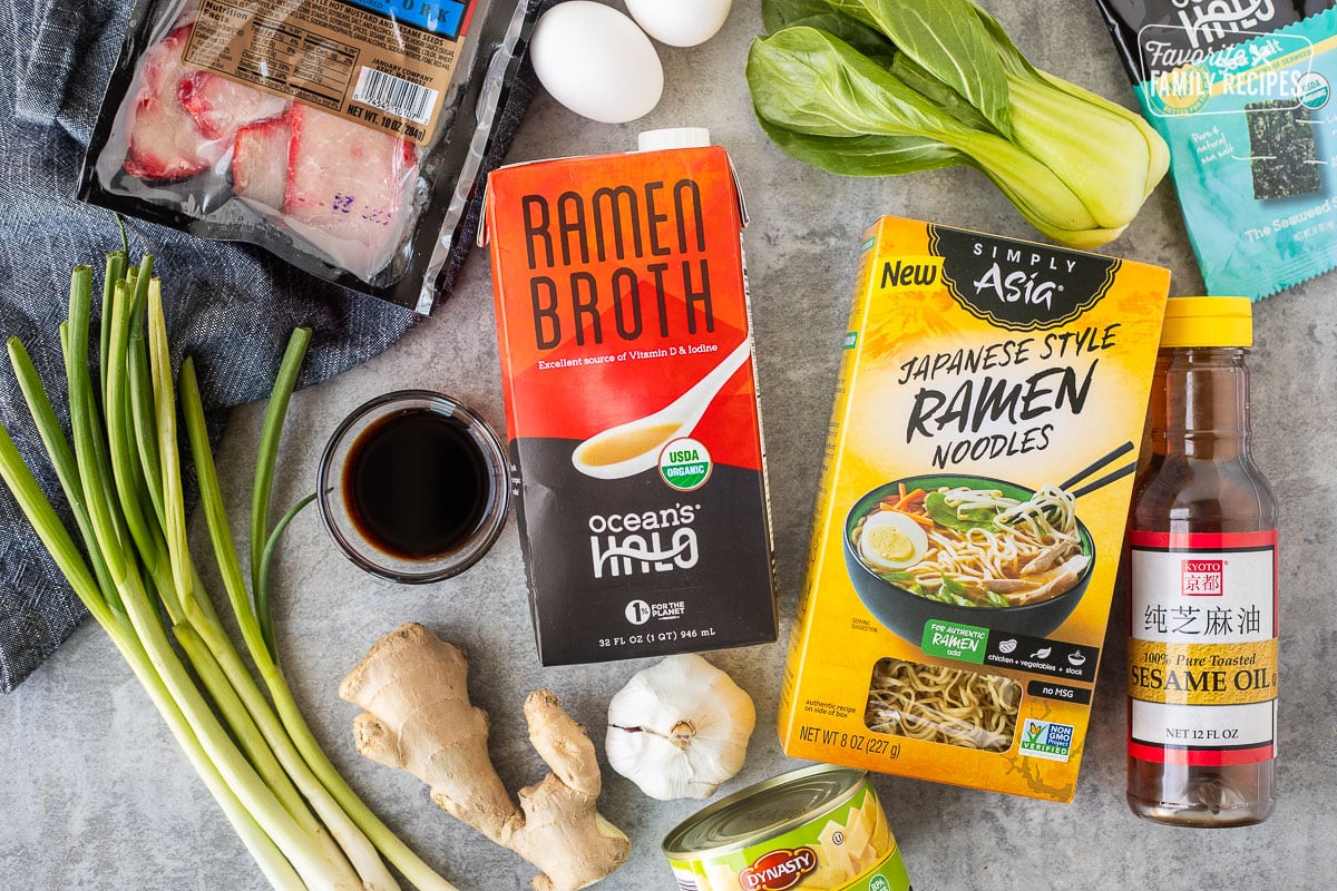 Ingredients to make Shoyu Ramen including Ramen noodles, Ramen broth, sesame oil, garlic, ginger, soy sauce, green onion, eggs, seaweed sheets, bamboo, bok choy and barbecue pork loin.