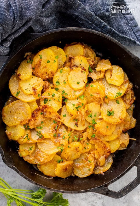 Skillet of Smothered Potatoes garnished with fresh parsley.