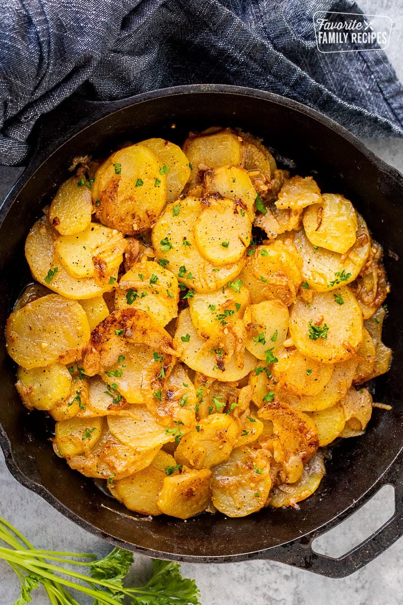 Skillet of Smothered Potatoes garnished with fresh parsley.