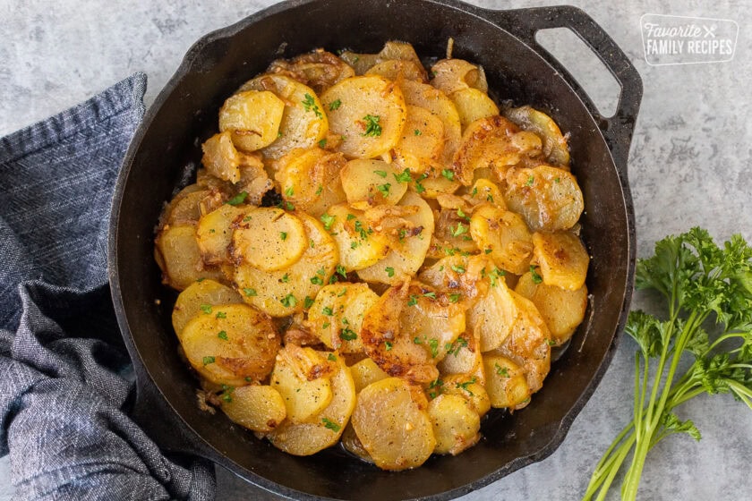 Skillet of Smothered Potatoes garnished with fresh parsley.