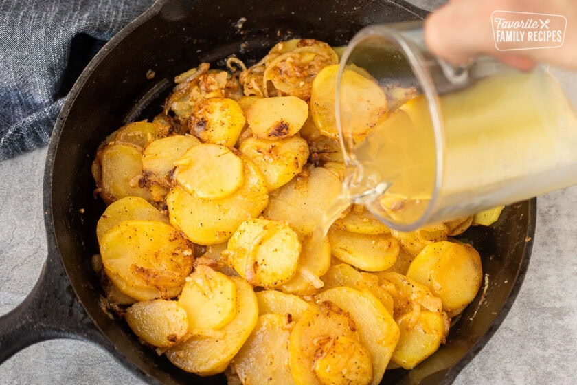 Pouring broth on cooked potatoes.