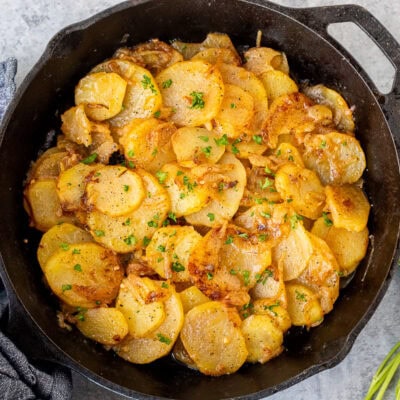 Skillet of Smothered Potatoes garnished with fresh parsley.