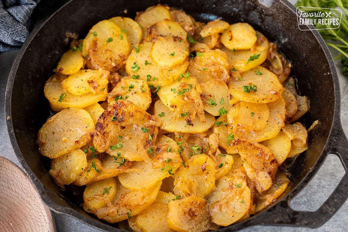 Skillet of Smothered Potatoes garnished with fresh parsley.