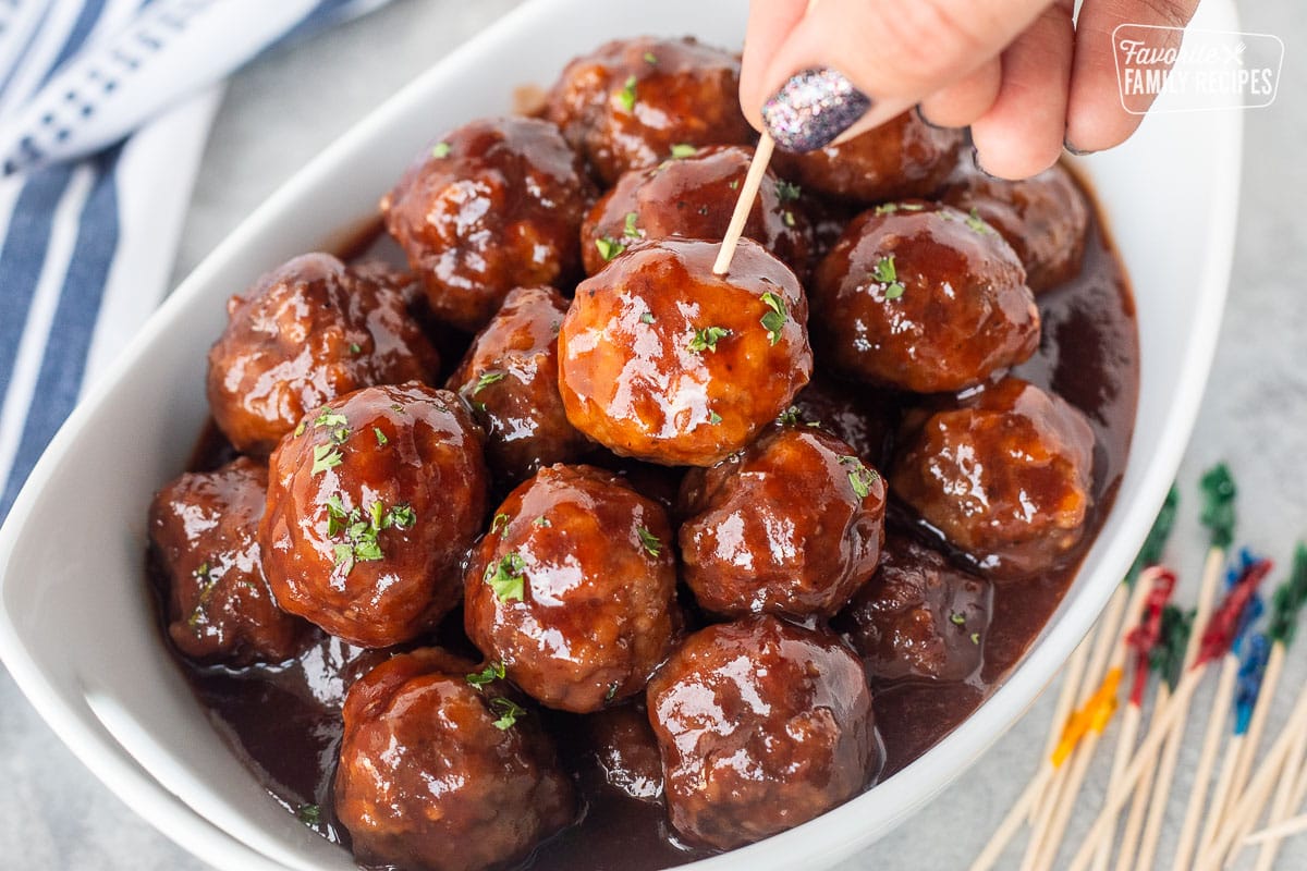 Grape jelly meatballs garnished with fresh parsley stabbed with a toothpick.