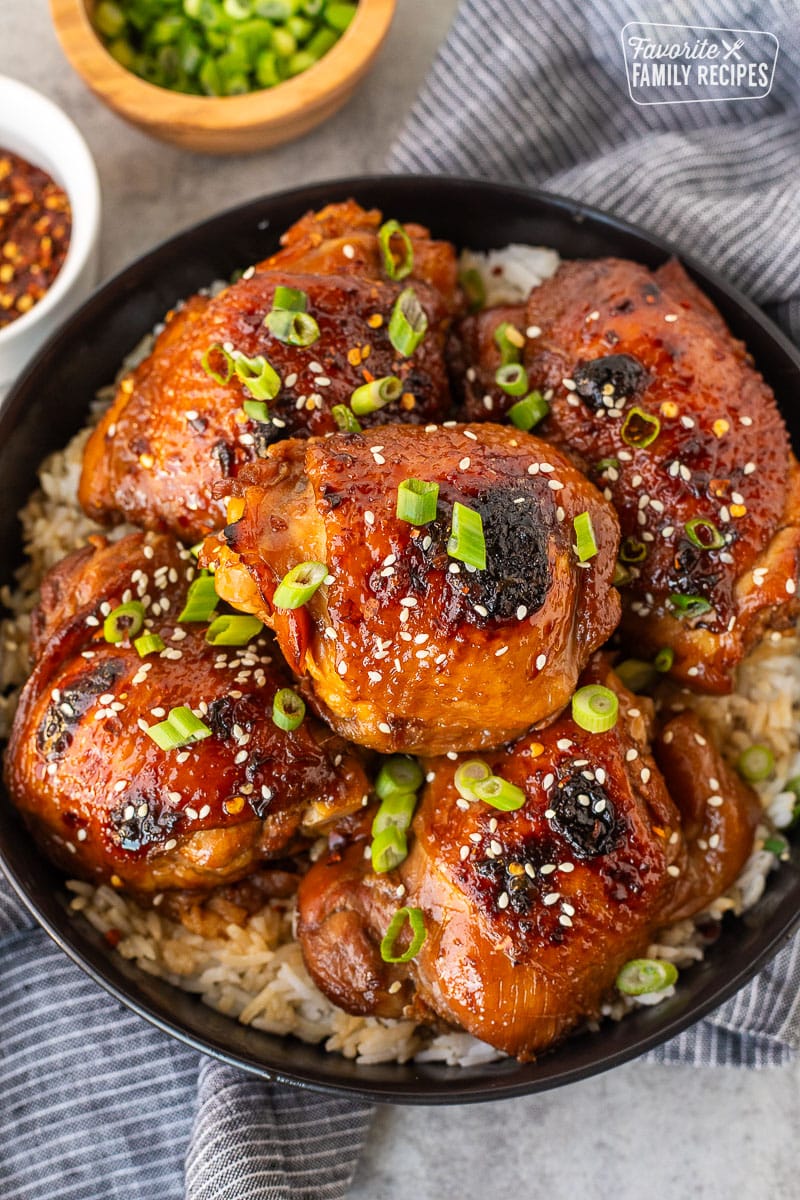 Plate with white rice and five pieces of Shoyu chicken topped with fresh slices of green onion and sesame seeds.