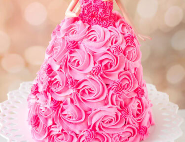 Barbie cake with pink swirls of frosting on a cake stand.