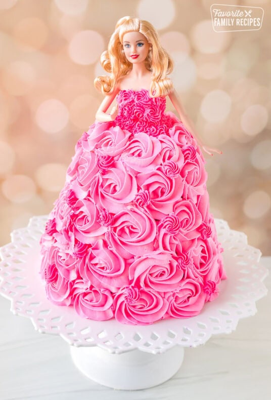 Barbie cake with pink swirls of frosting on a cake stand.