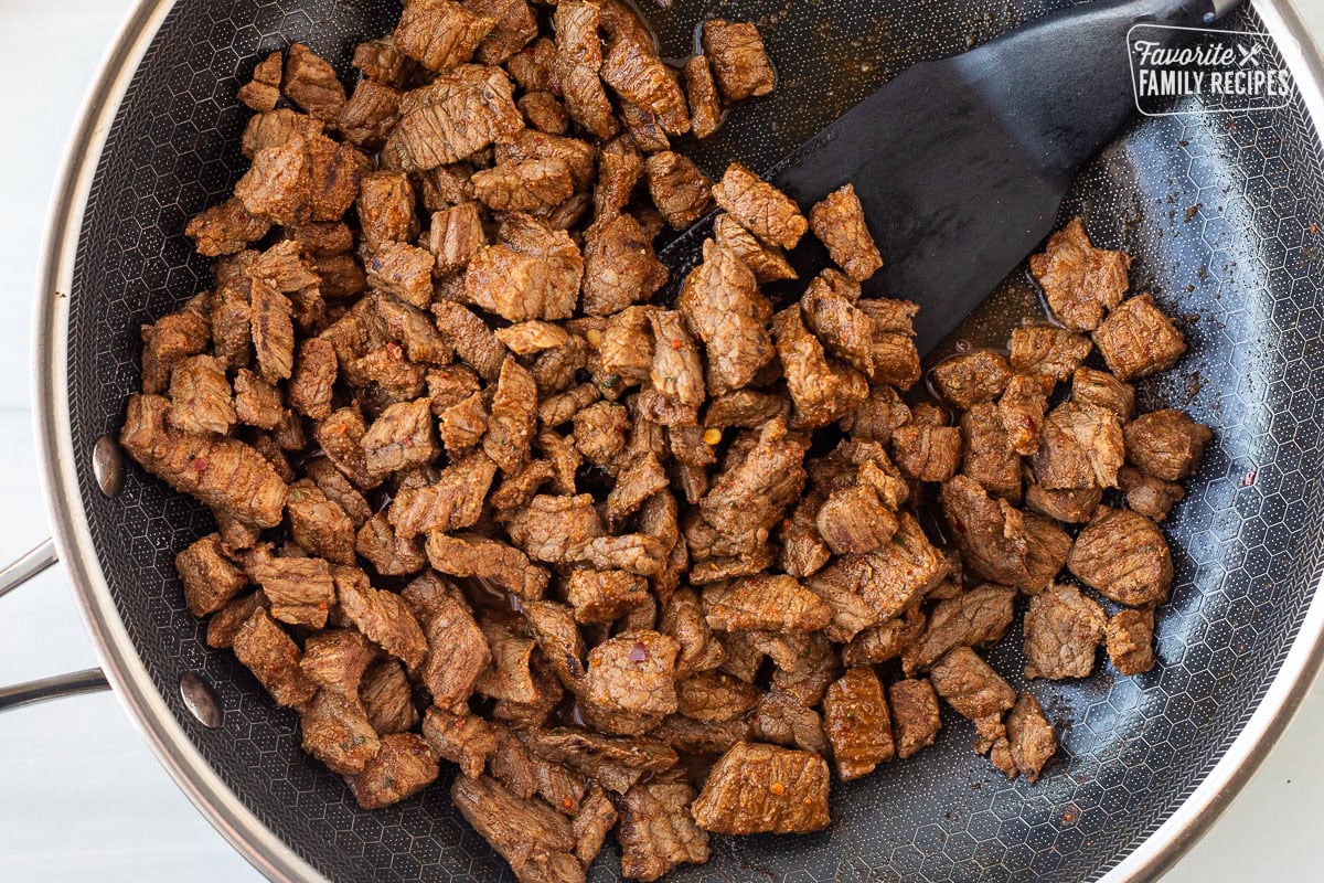 Skillet with cooked Carne Asada cut up and seasoned.