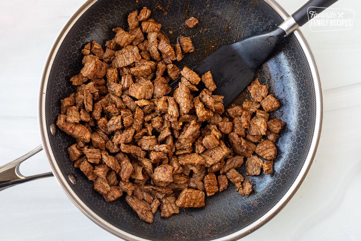 Carne Asada Seasoning on chopped carne asada meat cooked in a skillet.