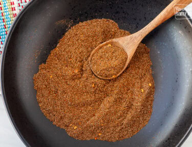 Bowl of Carne Asada Seasoning mixed with a wooden spoon.