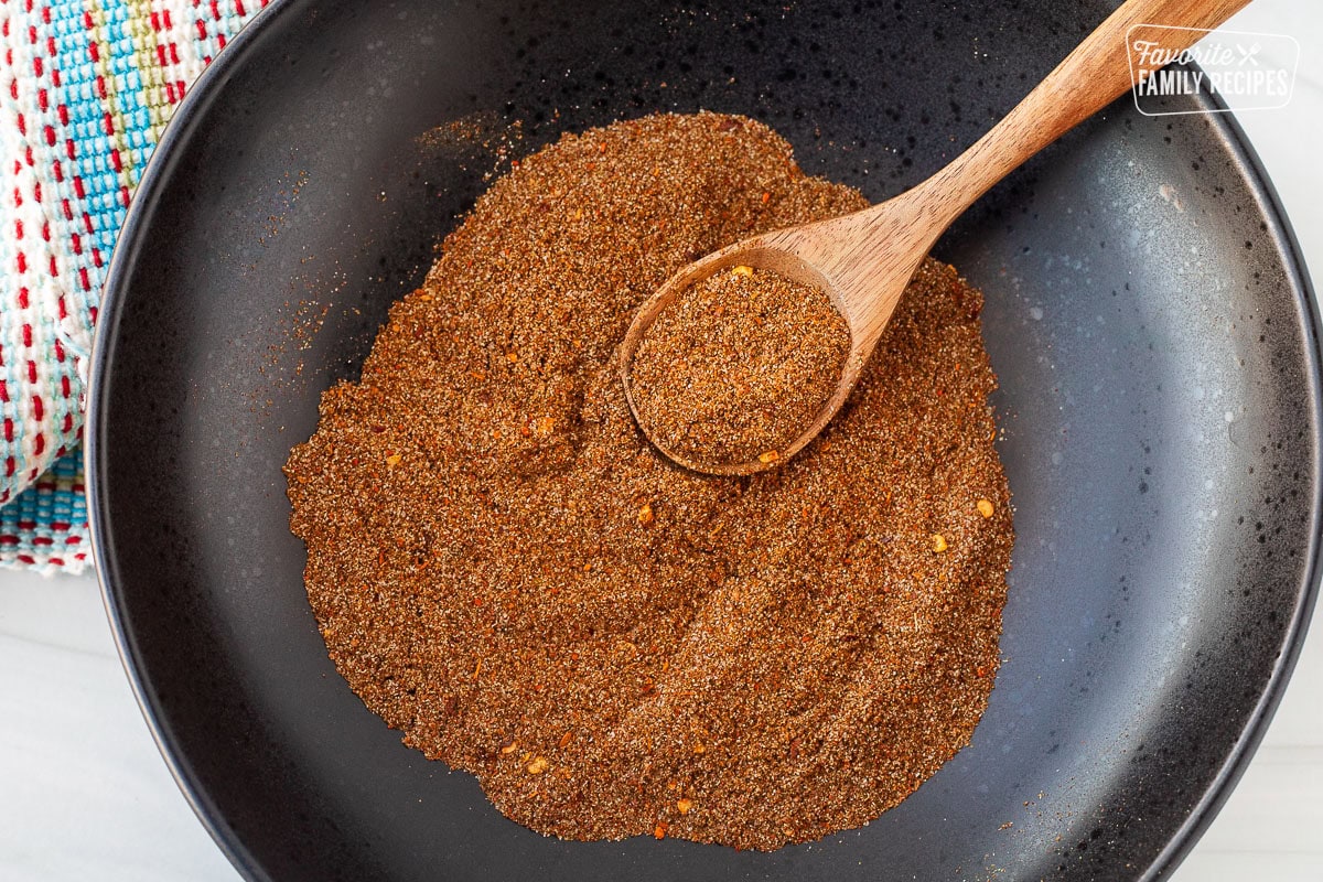 Bowl of Carne Asada Seasoning mixed with a wooden spoon perfect to use as a rub for skirt steak and carne asada.