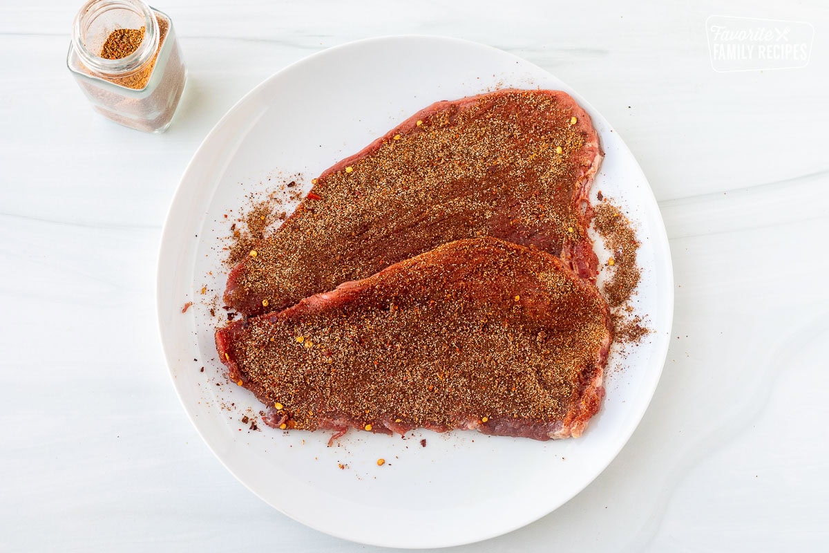 Carne Asada Seasoning rubbed onto Carne Asada meat on a glass plate.