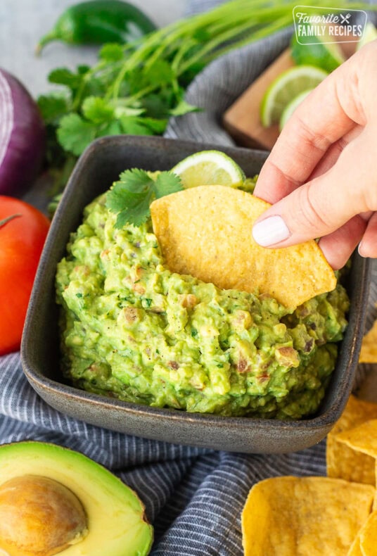 Dipping a tortilla chip into a bowl of guacamole.