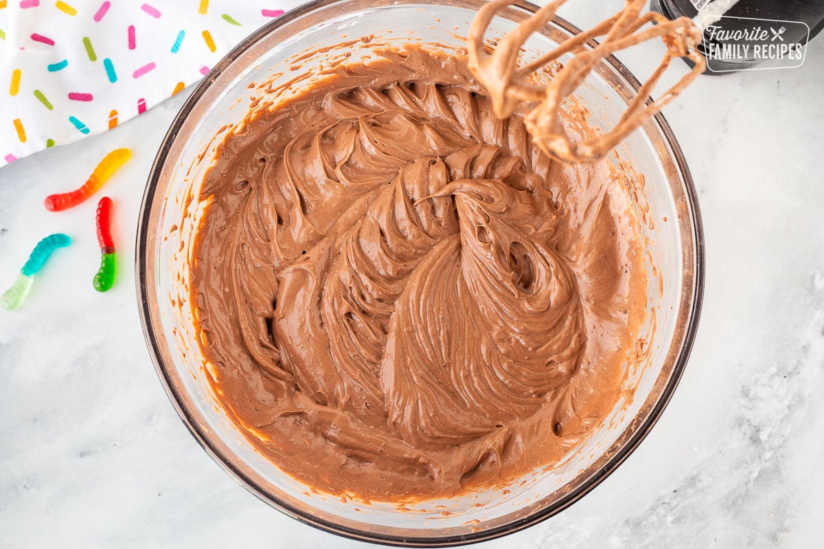 Glass mixing bowl with whipped pudding and cream cheese mixture with electric beaters.