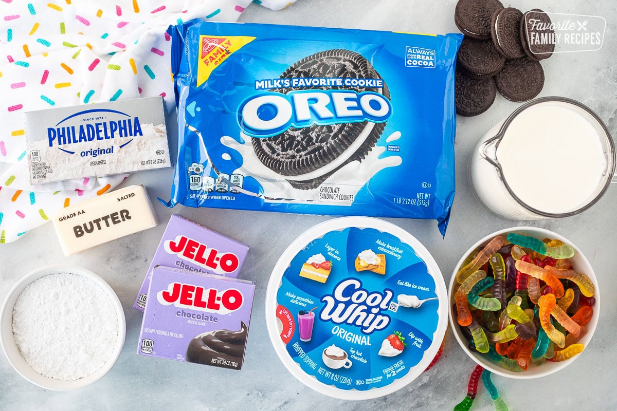 Ingredients to make Dirt Cake including Oreos, milk, gummy worms, Cool Whip, Jello chocolate pudding mixes, powdered sugar, butter and cream cheese.