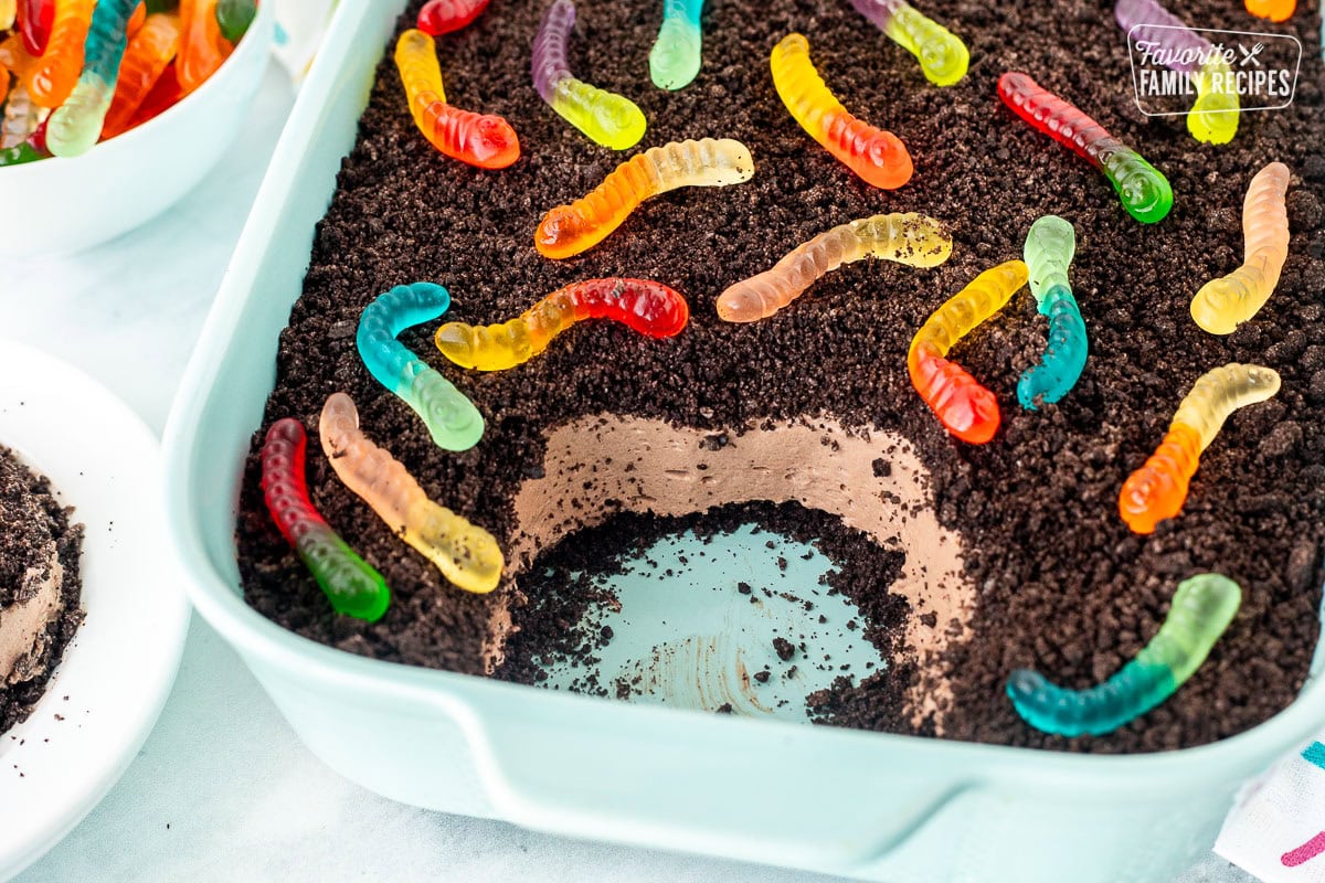 Scoop out of dirt cake with gummy worms from a glass baking dish.