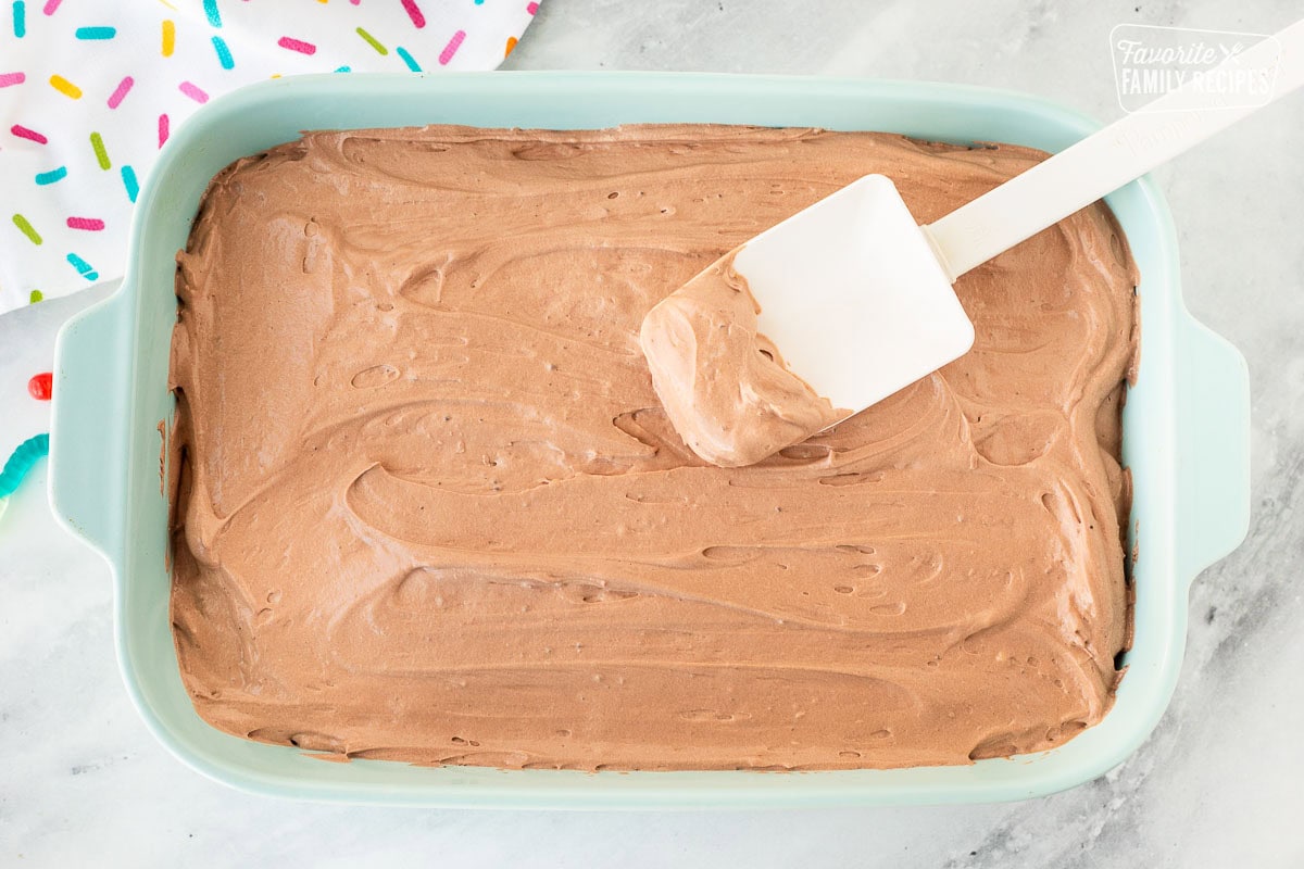 Spread out chocolate filling for Dirt Cake in a 9x13 dish with a spatula.