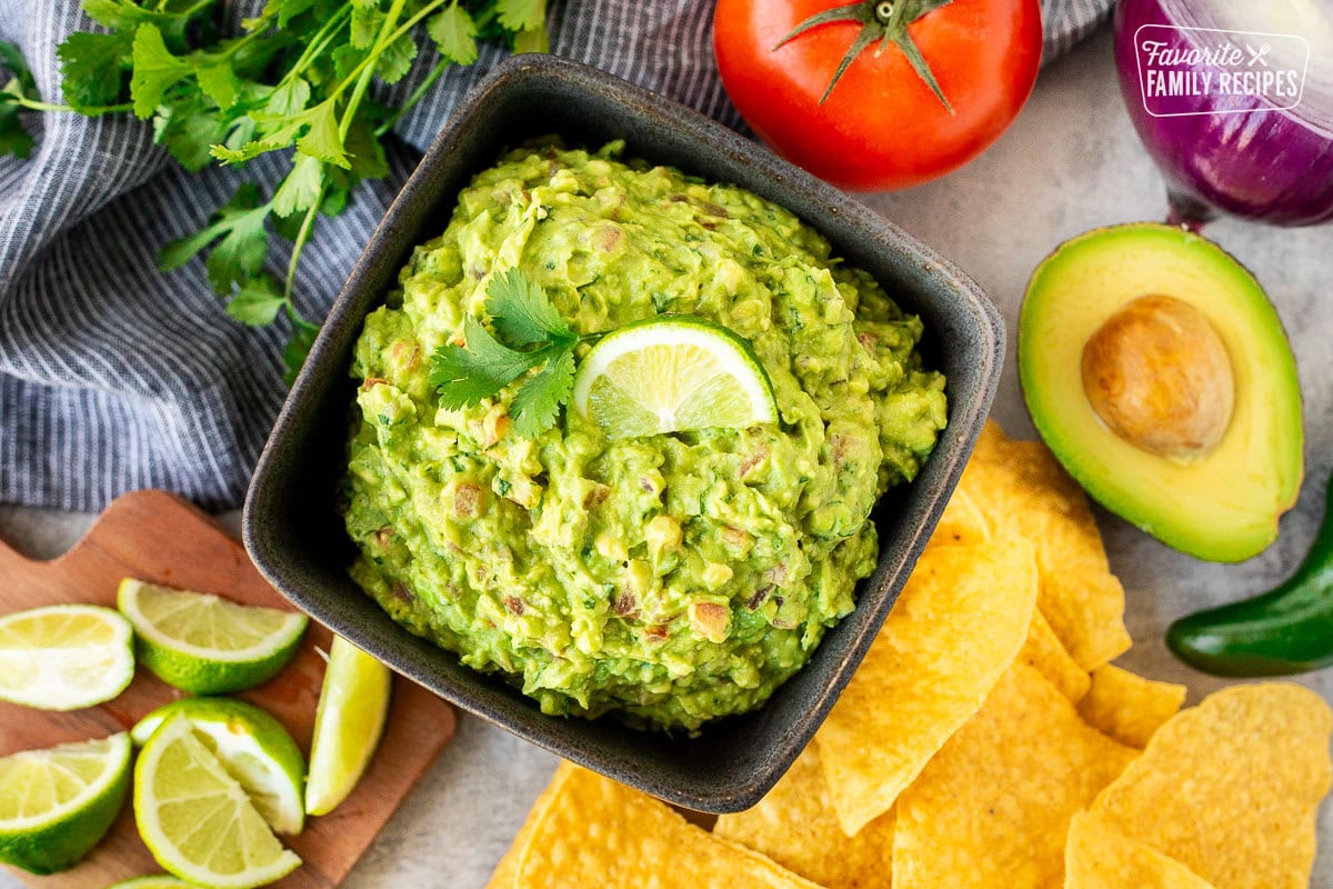 Guacamole in a bowl garnished with fresh lime and cilantro.