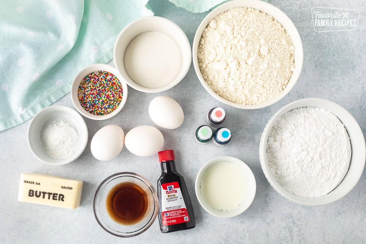 Ingredients to make Italian Easter cookies including flour, powdered sugar, milk, sugar, baking powder, salt, eggs, butter, vanilla, almond extract, sprinkles and coloring.